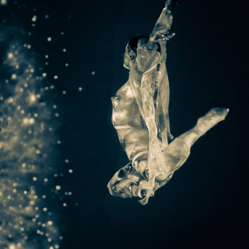 A person in a flowing, translucent outfit leaps gracefully in midair against a dark background with glowing, star-like particles on the left side, evoking the dynamic energy of e-commerce innovation.