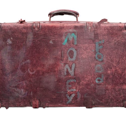 A weathered, vintage maroon suitcase against a white background. The word “MONEY” is vertically stenciled in teal on the center of the suitcase, with the word “FOOD” stenciled vertically next to it in a smaller, lighter font—evoking themes of e-commerce and travel essentials converging in timeless style.